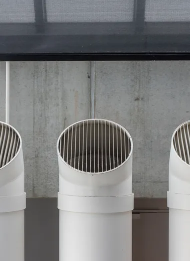 Gaines de ventilation industrielles blanches devant un mur en béton
