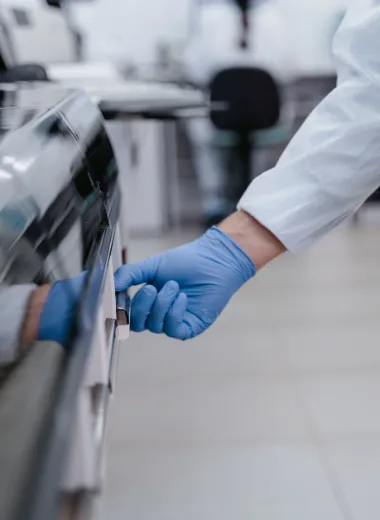 Main en gant bleu ouvrant un équipement de laboratoire